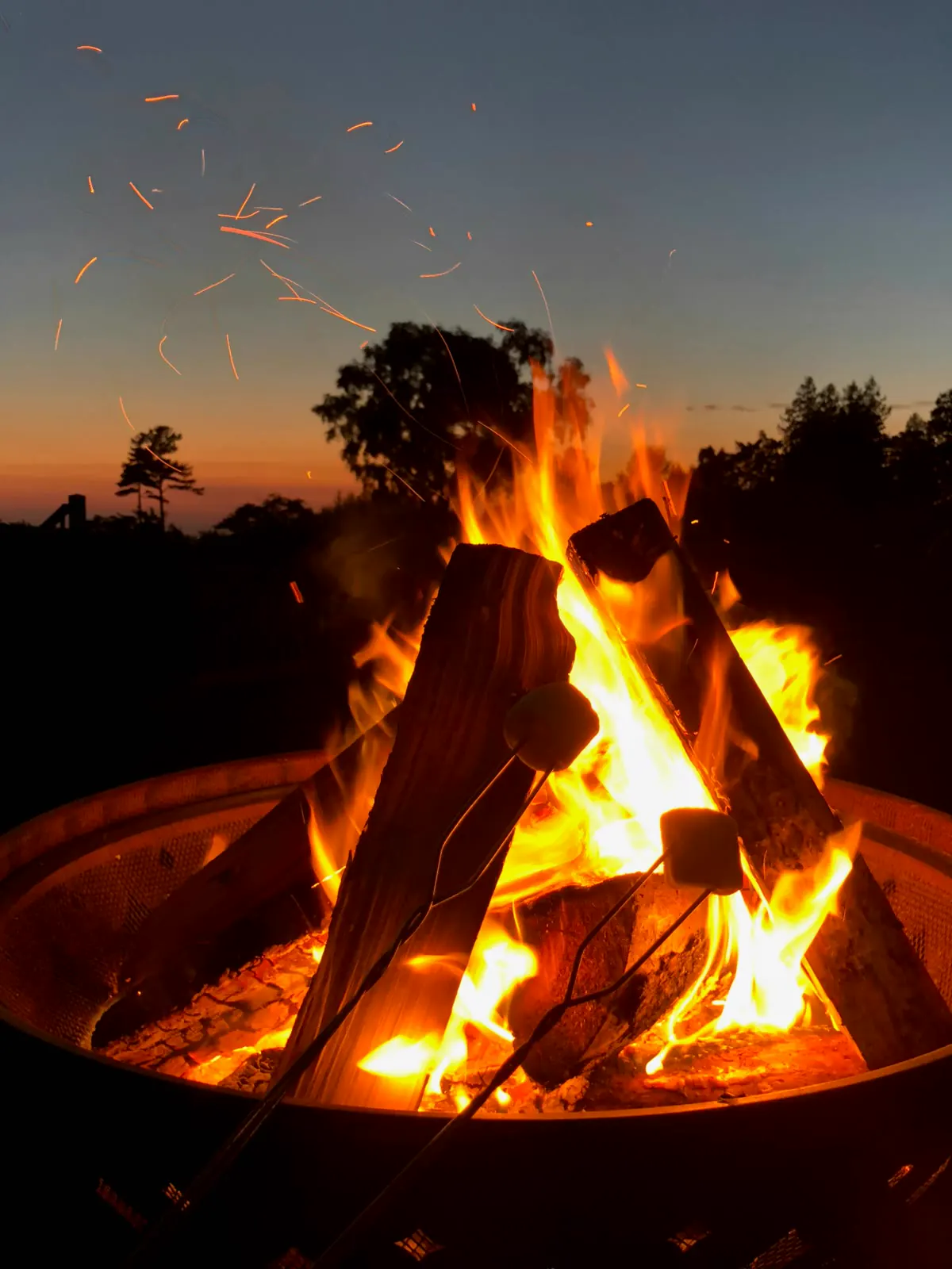 Roasting marshmallows over a campfire at dusk