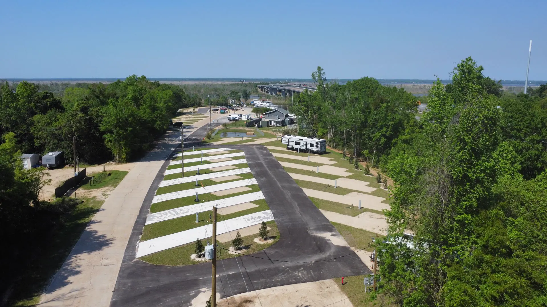 Aerial view of the full-hookup RV sites at Swamp House RV Park, with the marina and bay in the distance